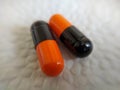 Black and orange pills on a white napkin close-up Royalty Free Stock Photo