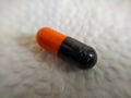 Black and orange pills on a white napkin close-up Royalty Free Stock Photo