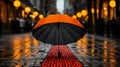 a black and orange umbrella sitting on the ground in the rain Royalty Free Stock Photo