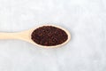 Black organic quinoa or Ragi, millet seeds in wooden spoon, top view. Grey background, copy space