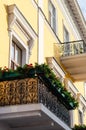 Black ornate wrought iron balcony decorated with flowers. Boxes with red geraniums. Bottom side view