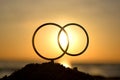 Black outlines wedding rings at dawn sunset on seashore. Stick contours in shape