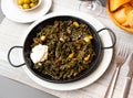 Black paella with cuttlefish ink and seafood in black pan in Spanish restaurant. Traditional dish of Spanish cuisine Royalty Free Stock Photo