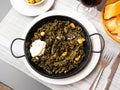 Black paella with cuttlefish ink and seafood in black pan in Spanish restaurant. Traditional dish of Spanish cuisine Royalty Free Stock Photo