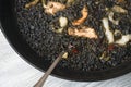 Black paella with cuttlefish ink and seafood in a black pan in a Spanish restaurant. Royalty Free Stock Photo