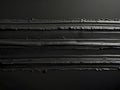 Black paint brushstrokes layering with subtle light reflections, forming textured abstract background, adding depth and Royalty Free Stock Photo