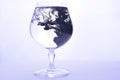 Black paint in water in a crystal glass on a white background Royalty Free Stock Photo