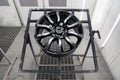 A black painted aluminum alloy wheel is mounted on a special frame during drying in a chamber in a vehicle body repair workshop. Royalty Free Stock Photo