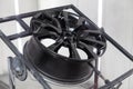 A black painted aluminum alloy wheel is mounted on a special frame during drying in a chamber in a vehicle body repair workshop. Royalty Free Stock Photo