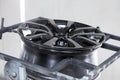 A black painted aluminum alloy wheel is mounted on a special frame during drying in a chamber in a vehicle body repair workshop. Royalty Free Stock Photo