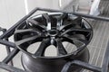 A black painted aluminum alloy wheel is mounted on a special frame during drying in a chamber in a vehicle body repair workshop. Royalty Free Stock Photo