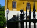 black painted cast iron fence in diminishing perspective with yellow facade background Royalty Free Stock Photo