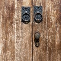 Black painted old door handle, knocker and copper lock over a brown wooden door with visible texture Royalty Free Stock Photo