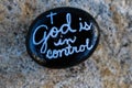 Black painted rock with message stating God is in control