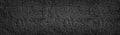 Black painted stone wall wide texture. Dark coarse pebbledash panoramic background Royalty Free Stock Photo