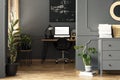 Black painting above desk with lamp and desktop computer in grey Royalty Free Stock Photo