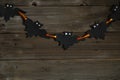 Halloween background with a garland of bats made of black cardboard on a bright orange ribbon Royalty Free Stock Photo