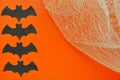 Black paper bats lie on orange background with cobwebs