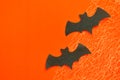 Black paper bats lie on orange background with cobwebs