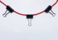 Black paper binder clip hanging on red rope isolate on white background Royalty Free Stock Photo