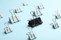 Black paper binder clip among white ones on light blue background. Racism concept Royalty Free Stock Photo