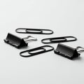 Black paper clips and binder clips are arranged on a plain white surface. The paper cli Royalty Free Stock Photo