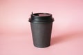 Black paper coffee mug on a pinkbackground. Empty space for text and design. The form for the name of the coffee or company or Royalty Free Stock Photo