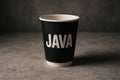 Black paper java cup on concrete surface with bold white text shown in closeup minimal branding design. Royalty Free Stock Photo