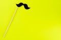 Black paper mustache with copy space for text on yellow background.