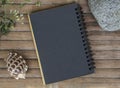 Black paper notebook on rustic wood background with natural decor. Royalty Free Stock Photo