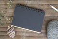 Black paper notebook on rustic wooden background with natural decor. Type or message mockup. Royalty Free Stock Photo