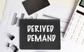 Black paper with text derived demand on financial documents with calculator, push pins and binder clips Royalty Free Stock Photo