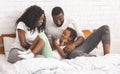Black parents tickling their daughter while lying in bed together Royalty Free Stock Photo