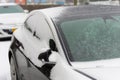 Black parked car covered with thick layer of ice and snow in the street