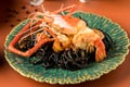 Black pasta with shrimps on a green plate. Black Italian seafood pasta with shrimps and greens on white restaurant plate. Black ho Royalty Free Stock Photo