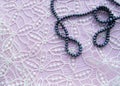 Black pearl beads on a delicate pink lace background, flat lay, top view Royalty Free Stock Photo