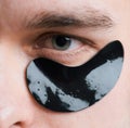 Black pearl extract. Skin care. Minimizes puffiness and reduce dark circles. Eye patches for men. Man with black eye Royalty Free Stock Photo