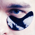 Black pearl extract. Skin care. Minimizes puffiness and reduce dark circles. Eye patches for men. Man with black eye Royalty Free Stock Photo