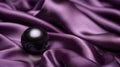 A black pearl lies on purple satin, the fabric luxurious folds background Royalty Free Stock Photo