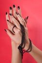 Women hands with black nails and pearls necklace on red background Royalty Free Stock Photo