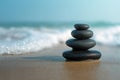 Black pebble stack on wet sand with ocean waves in background. Zen balance concept Royalty Free Stock Photo