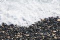 Black pebbles on the seashore washed by the sea wave. Sea coast in the resort of the island of Cyprus