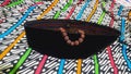 Black peci and brown prayer beads on traditional Javanese Indonesian batik motif cloth