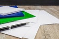 Black pen, colored folders for documents, envelopes, notebooks, stationery on the table.