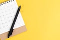 Black pen on desktop calendar in flat lay or top view on yellow background with copy space using as writing plan, circle on