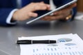 Black pen lying over business analytics papers. Businessman hands using tablet at the background Royalty Free Stock Photo
