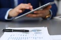 Black pen lying over business analytics papers. Businessman hands using tablet at the background Royalty Free Stock Photo