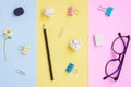 Black Pencil,Eraser,Paper Clips,Eyeglasses and White Flower on Pink,Yellow and Blue Background Royalty Free Stock Photo