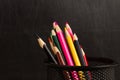 Black pencil holder full of colorful pencils, isolated over school blackboard background Royalty Free Stock Photo