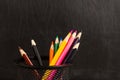 Black pencil holder full of colorful pencils, isolated over school blackboard background Royalty Free Stock Photo